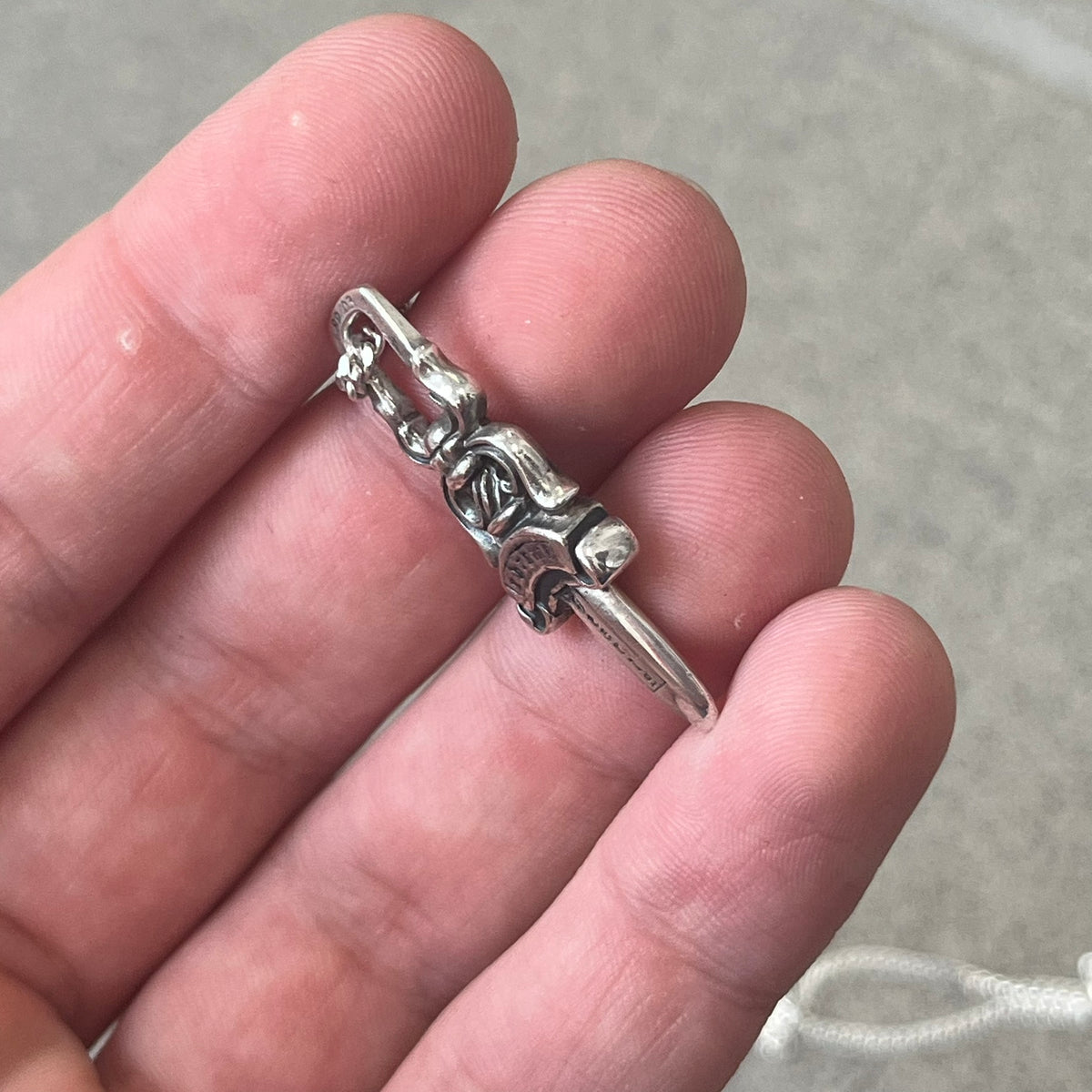Chrome Hearts Dagger Zipper Pendant crafted from .925 silver, featuring the brand’s signature double-sided dagger design with “Chrome” on the guard and “Hearts” on the blade. Comes on a standard 925 Silver chain (non-CH). Square bail for chain attachment with 925 tag on one side and 89 03 on the other. The dagger was originally a zipper pull.