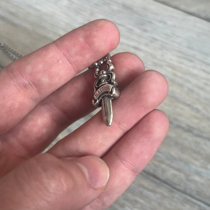 Chrome Hearts Dagger Zipper Pendant crafted from .925 silver, featuring the brand’s signature double-sided dagger design with “Chrome” on the guard and “Hearts” on the blade. Comes on a standard steel ball chain (non-CH). Square bail for chain attachment with 925 tag on one side and 89 03 on the other. The dagger was originally a zipper pull.
