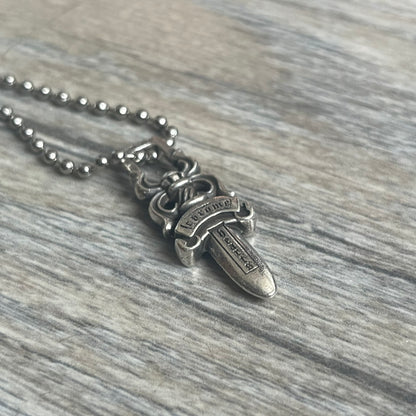 Chrome Hearts Dagger Zipper Pendant crafted from .925 silver, featuring the brand’s signature double-sided dagger design with “Chrome” on the guard and “Hearts” on the blade. Comes on a standard steel ball chain (non-CH). Square bail for chain attachment with 925 tag on one side and 89 03 on the other. The dagger was originally a zipper pull.