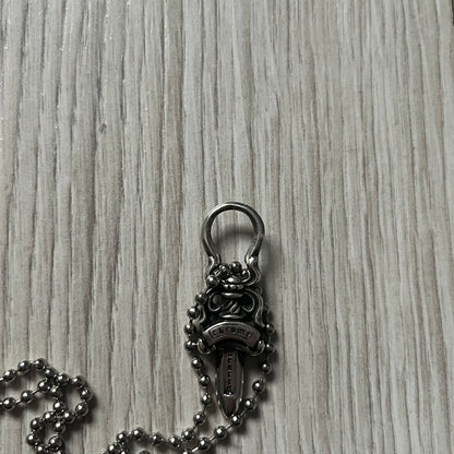 Chrome Hearts Dagger Zipper Pendant crafted from .925 silver, featuring the brand’s signature double-sided dagger design with “Chrome” on the guard and “Hearts” on the blade. Comes on a standard steel ball chain (non-CH). Circular bail for chain attachment. The dagger was originally a zipper pull.