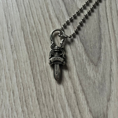 Chrome Hearts Dagger Zipper Pendant crafted from .925 silver, featuring the brand’s signature double-sided dagger design with “Chrome” on the guard and “Hearts” on the blade. Comes on a standard steel ball chain (non-CH). Circular bail for chain attachment. The dagger was originally a zipper pull.