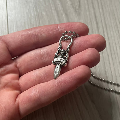 Chrome Hearts Dagger Zipper Pendant crafted from .925 silver, featuring the brand’s signature double-sided dagger design with “Chrome” on the guard and “Hearts” on the blade. Comes on a standard steel ball chain (non-CH). Circular bail for chain attachment. The dagger was originally a zipper pull.