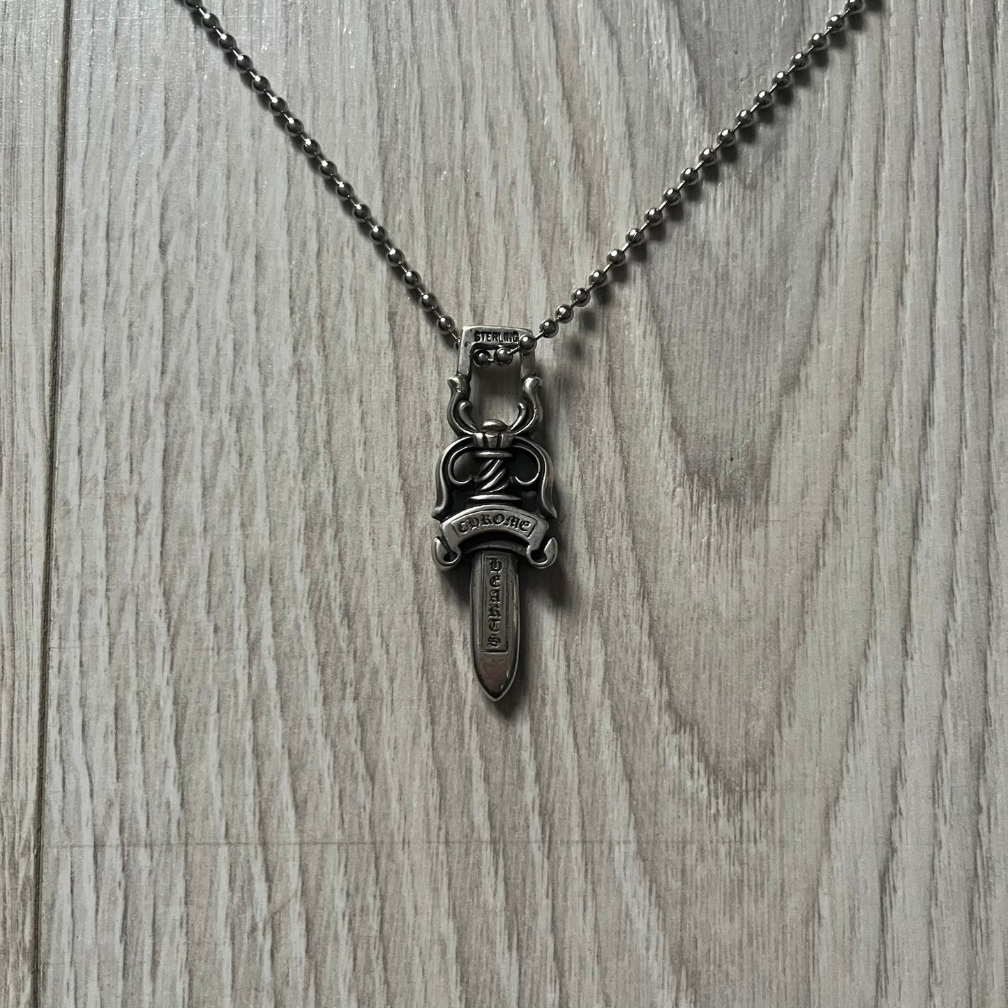 Chrome Hearts Dagger #10 Pendant crafted from genuine .925 silver, featuring the brand’s signature double-sided dagger design with “Chrome” on the guard and “Hearts” on the blade. Comes on a standard steel ball chain (non-CH). The top rectangular bail includes engraved markings: “89/03” on one side and “Sterling” on the other.