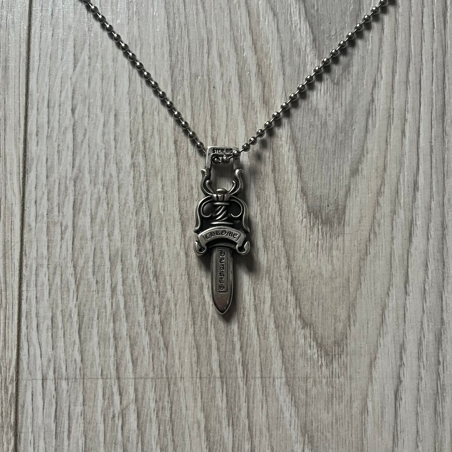 Chrome Hearts Dagger #10 Pendant crafted from genuine .925 silver, featuring the brand’s signature double-sided dagger design with “Chrome” on the guard and “Hearts” on the blade. Comes on a standard steel ball chain (non-CH). The top rectangular bail includes engraved markings: “89/03” on one side and “Sterling” on the other.