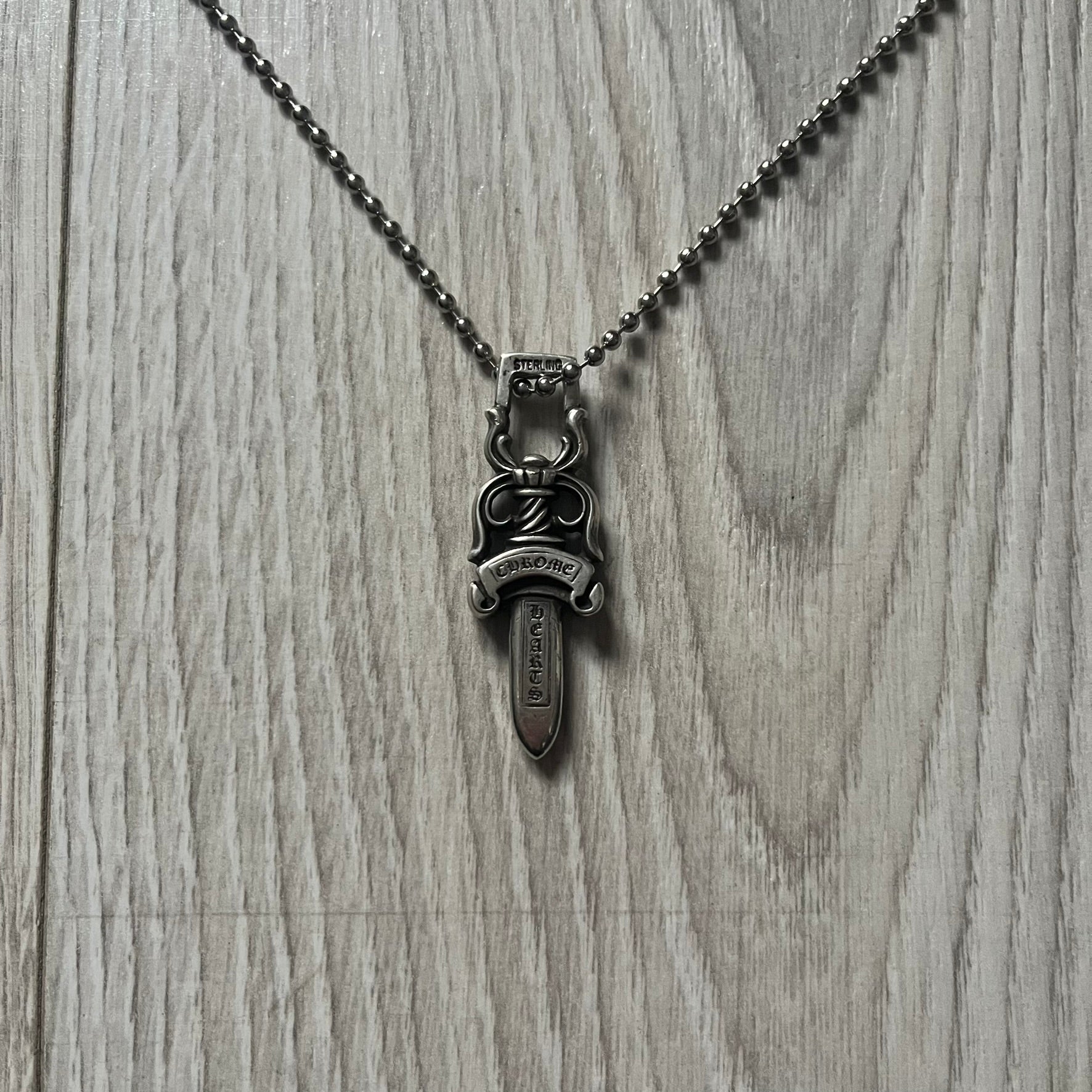 Chrome Hearts Dagger #10 Pendant crafted from genuine .925 silver, featuring the brand’s signature double-sided dagger design with “Chrome” on the guard and “Hearts” on the blade. Comes on a standard steel ball chain (non-CH). The top rectangular bail includes engraved markings: “89/03” on one side and “Sterling” on the other.