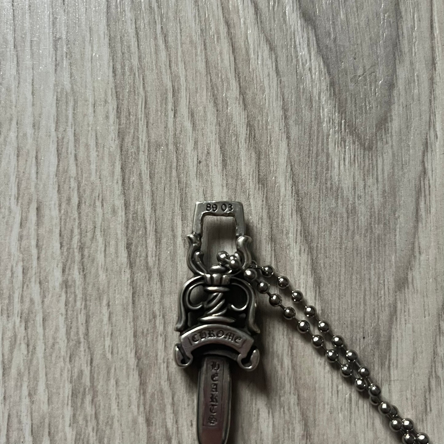 Chrome Hearts Dagger #10 Pendant crafted from genuine .925 silver, featuring the brand’s signature double-sided dagger design with “Chrome” on the guard and “Hearts” on the blade. Comes on a standard steel ball chain (non-CH). The top rectangular bail includes engraved markings: “89/03” on one side and “Sterling” on the other.