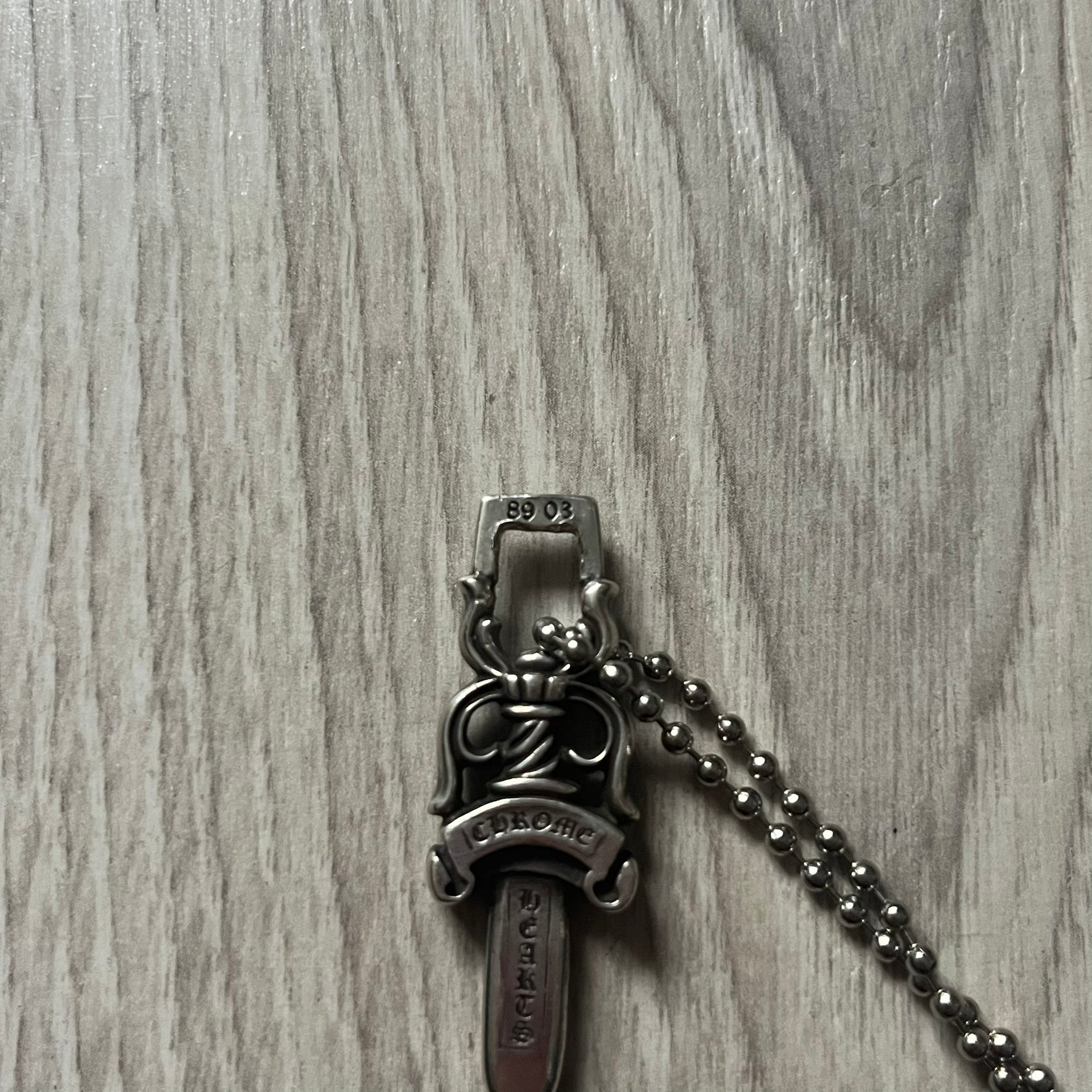 Chrome Hearts Dagger #10 Pendant crafted from genuine .925 silver, featuring the brand’s signature double-sided dagger design with “Chrome” on the guard and “Hearts” on the blade. Comes on a standard steel ball chain (non-CH). The top rectangular bail includes engraved markings: “89/03” on one side and “Sterling” on the other.