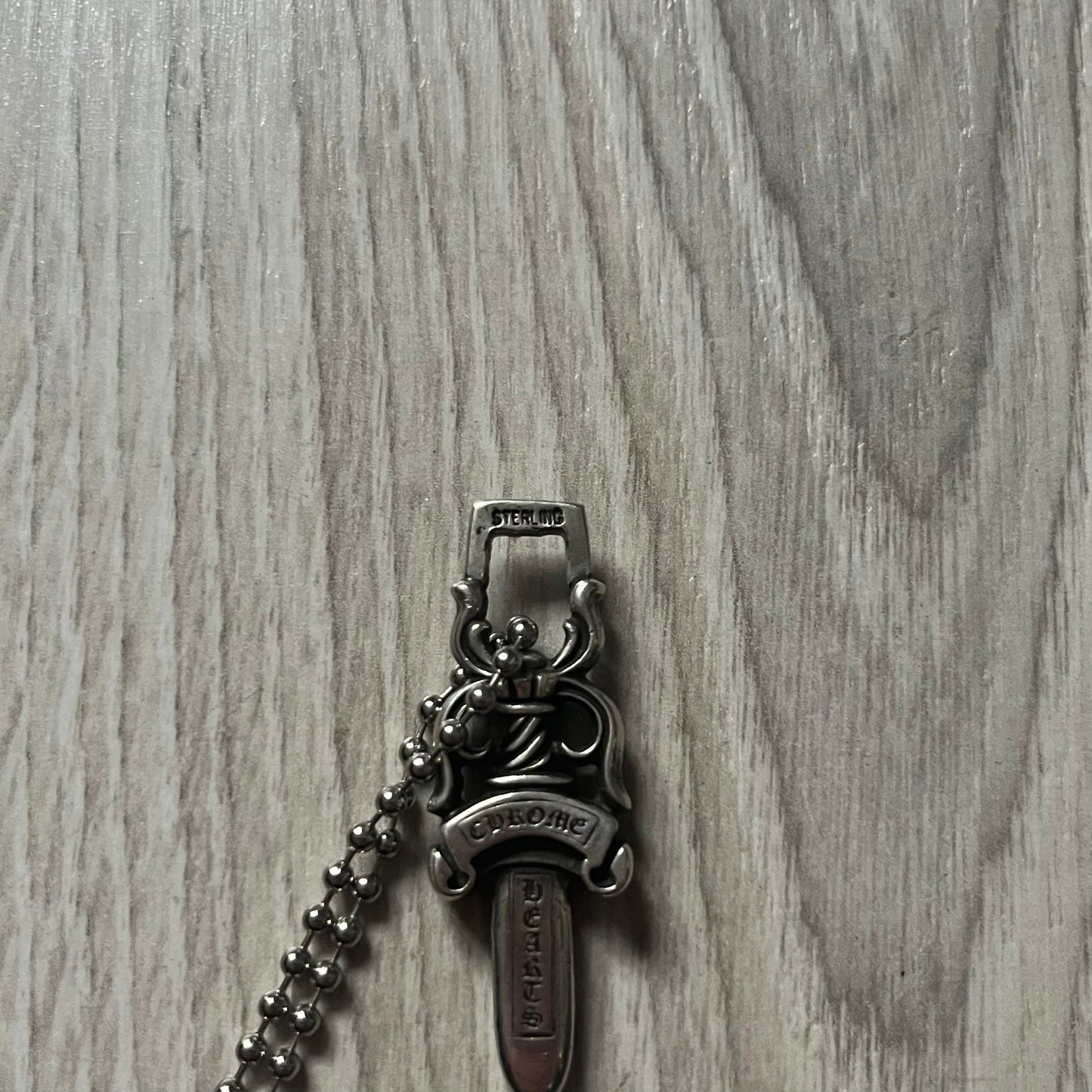 Chrome Hearts Dagger #10 Pendant crafted from genuine .925 silver, featuring the brand’s signature double-sided dagger design with “Chrome” on the guard and “Hearts” on the blade. Comes on a standard steel ball chain (non-CH). The top rectangular bail includes engraved markings: “89/03” on one side and “Sterling” on the other.