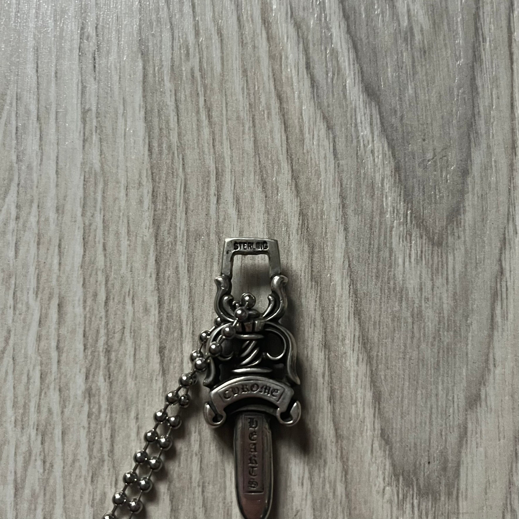 Chrome Hearts Dagger #10 Pendant crafted from genuine .925 silver, featuring the brand’s signature double-sided dagger design with “Chrome” on the guard and “Hearts” on the blade. Comes on a standard steel ball chain (non-CH). The top rectangular bail includes engraved markings: “89/03” on one side and “Sterling” on the other.