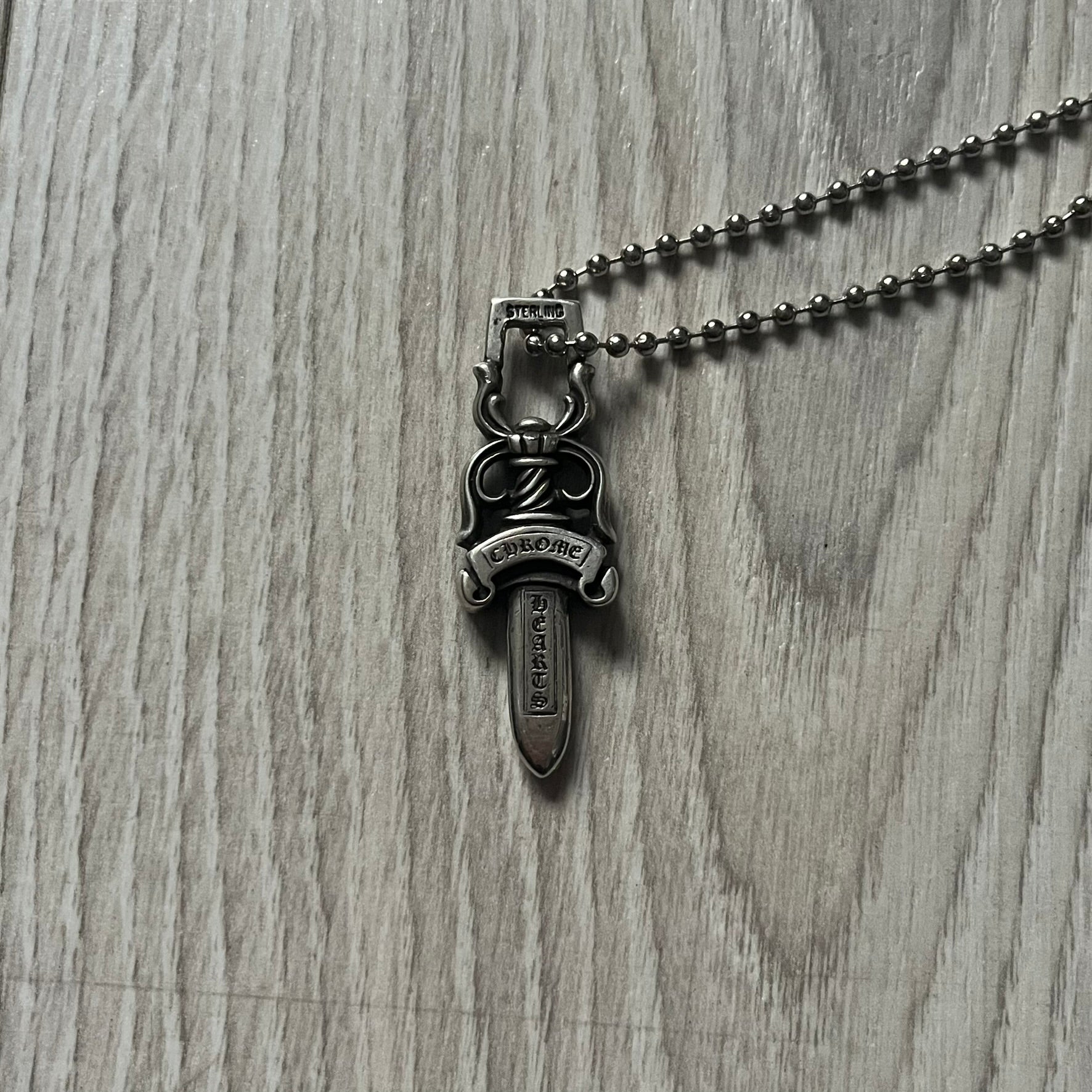 Chrome Hearts Dagger #10 Pendant crafted from genuine .925 silver, featuring the brand’s signature double-sided dagger design with “Chrome” on the guard and “Hearts” on the blade. Comes on a standard steel ball chain (non-CH). The top rectangular bail includes engraved markings: “89/03” on one side and “Sterling” on the other.