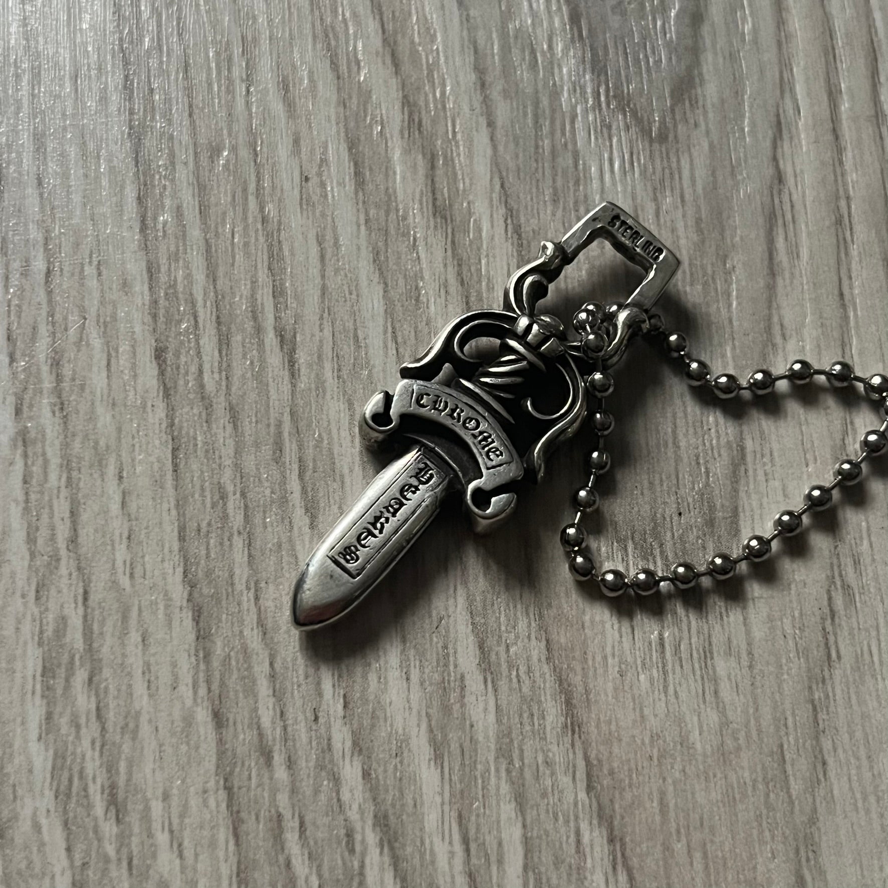 Chrome Hearts Dagger #10 Pendant crafted from genuine .925 silver, featuring the brand’s signature double-sided dagger design with “Chrome” on the guard and “Hearts” on the blade. Comes on a standard steel ball chain (non-CH). The top rectangular bail includes engraved markings: “89/03” on one side and “Sterling” on the other.