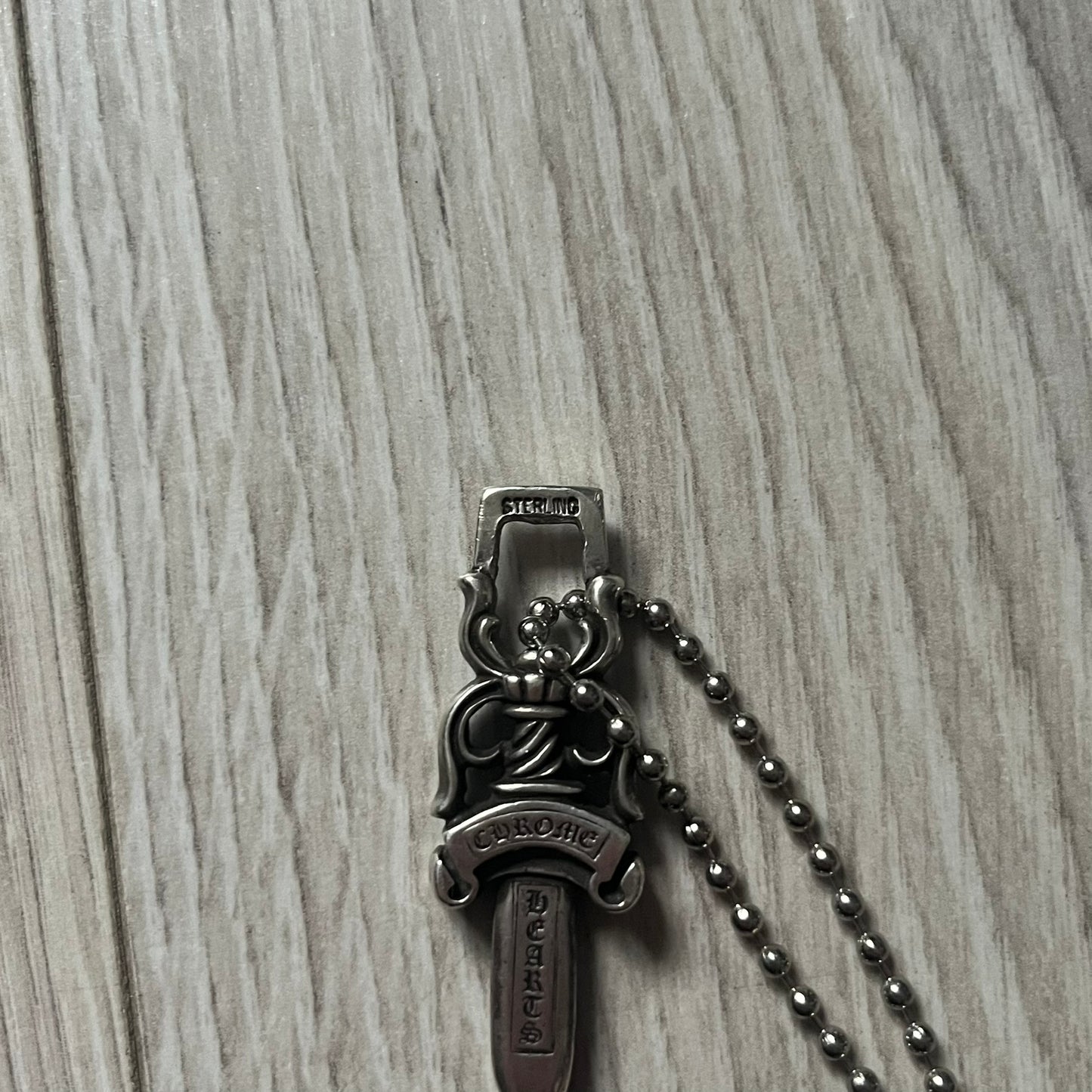 Chrome Hearts Dagger #10 Pendant crafted from genuine .925 silver, featuring the brand’s signature double-sided dagger design with “Chrome” on the guard and “Hearts” on the blade. Comes on a standard steel ball chain (non-CH). The top rectangular bail includes engraved markings: “89/03” on one side and “Sterling” on the other.&nbsp;