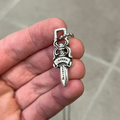 Chrome Hearts #5 Keychain Dagger Necklace crafted from .925 silver, featuring the brand’s signature double-sided dagger design with “Chrome” on the guard and “Hearts” on the blade. Comes on a stainless steel ball chain (non-CH). Square bail for chain attachment, the dagger was originally a keychain.