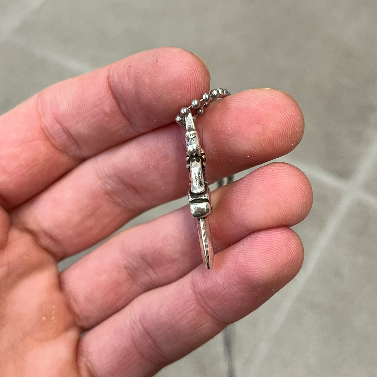 Chrome Hearts #5 Keychain Dagger Necklace crafted from .925 silver, featuring the brand’s signature double-sided dagger design with “Chrome” on the guard and “Hearts” on the blade. Comes on a stainless steel ball chain (non-CH). Square bail for chain attachment, the dagger was originally a keychain.