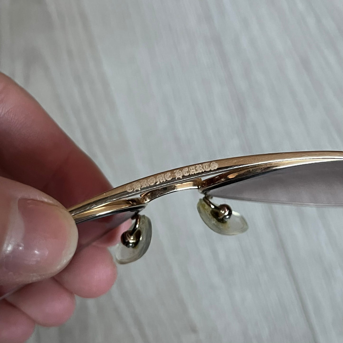 Chrome Hearts Stains Gold Sunglasses featuring a gold-tone metal frame with brown mirror-coated plastic lenses. Made in Japan, this model includes aged silver Chrome Hearts cross detailing wrapped around the arms, cut-out cross accents at the arm tips, and visible Chrome Hearts branding on the bridge and top of the frame. Additional cross branding appears on the nose pads. Comes complete with the original black leather Chrome Hearts zip case, finished with exterior branding and a dagger-shaped zipper pull.