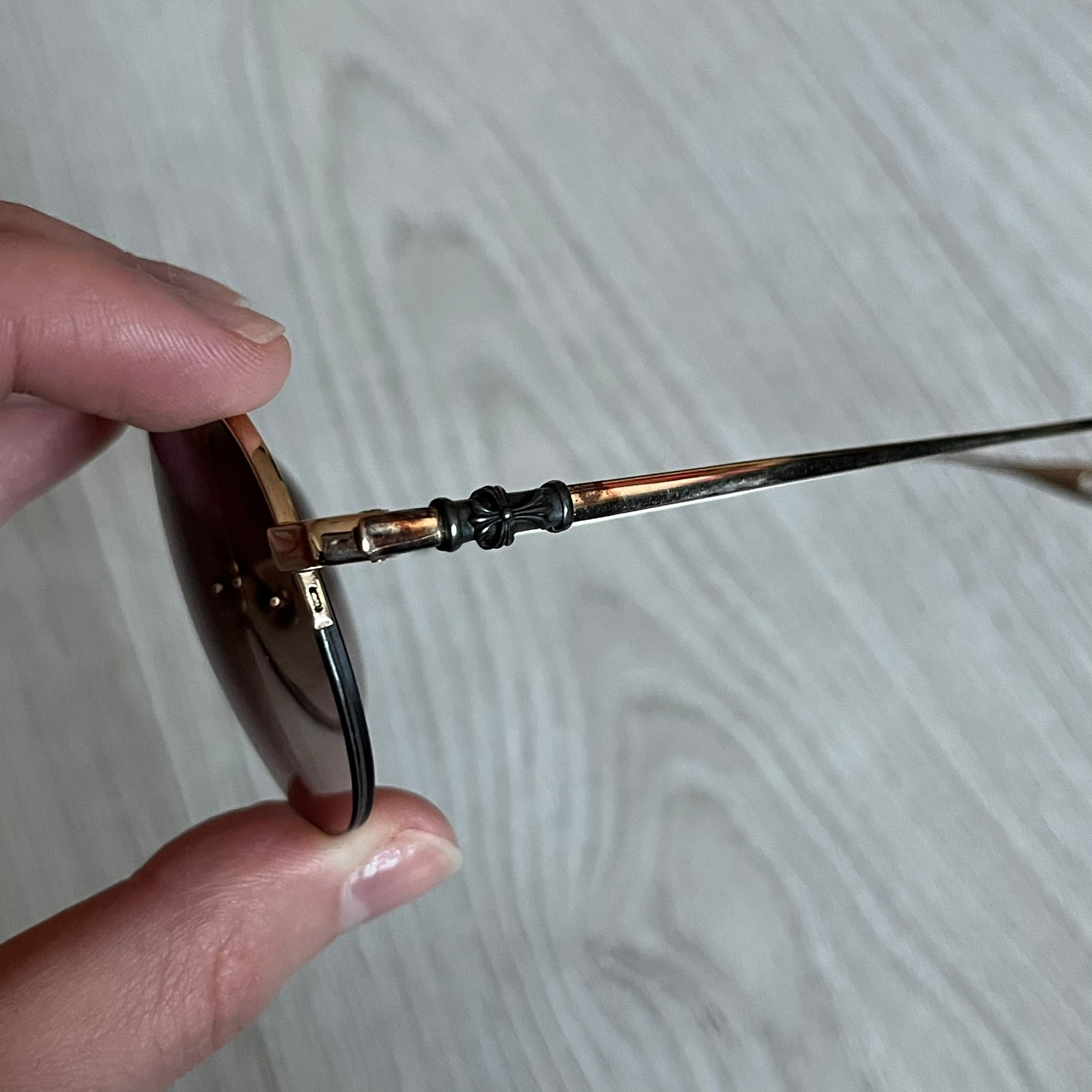 Chrome Hearts Stains Gold Sunglasses featuring a gold-tone metal frame with brown mirror-coated plastic lenses. Made in Japan, this model includes aged silver Chrome Hearts cross detailing wrapped around the arms, cut-out cross accents at the arm tips, and visible Chrome Hearts branding on the bridge and top of the frame. Additional cross branding appears on the nose pads. Comes complete with the original black leather Chrome Hearts zip case, finished with exterior branding and a dagger-shaped zipper pull.