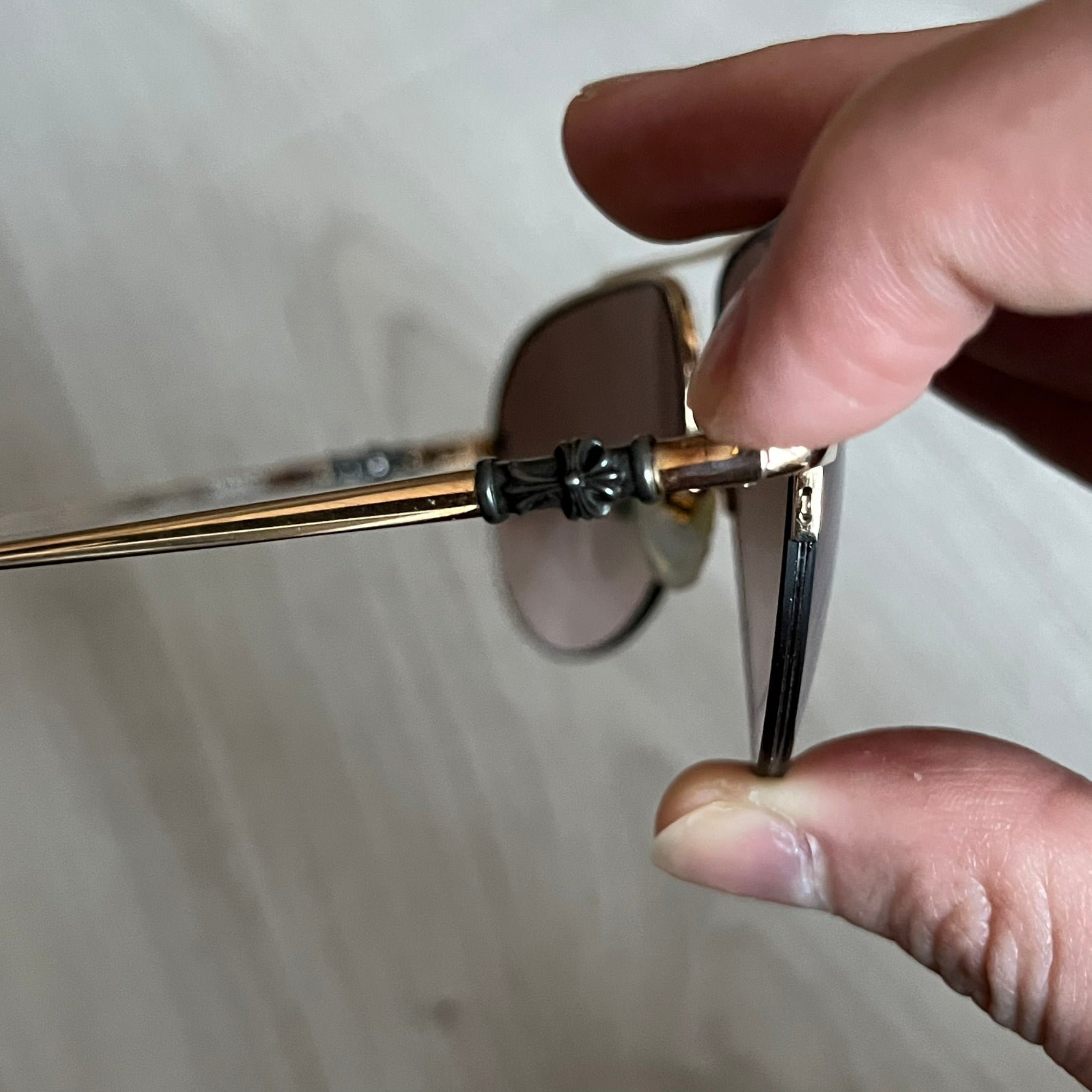 Chrome Hearts Stains Gold Sunglasses featuring a gold-tone metal frame with brown mirror-coated plastic lenses. Made in Japan, this model includes aged silver Chrome Hearts cross detailing wrapped around the arms, cut-out cross accents at the arm tips, and visible Chrome Hearts branding on the bridge and top of the frame. Additional cross branding appears on the nose pads. Comes complete with the original black leather Chrome Hearts zip case, finished with exterior branding and a dagger-shaped zipper pull.