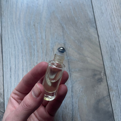 Chrome Hearts +22+ Roll-On Perfume features an aromatic oil blend with prominent jasmine and bergamot notes, designed as a concentrated roll-on fragrance. It is housed in a crystal bottle with a rhodium-plated sterling silver closure, hand crafted in France. The silver cap is detailed with raised Chrome Hearts crosses throughout, a larger cross on top, and embossed Chrome Hearts text wrapping around the base of the closure.