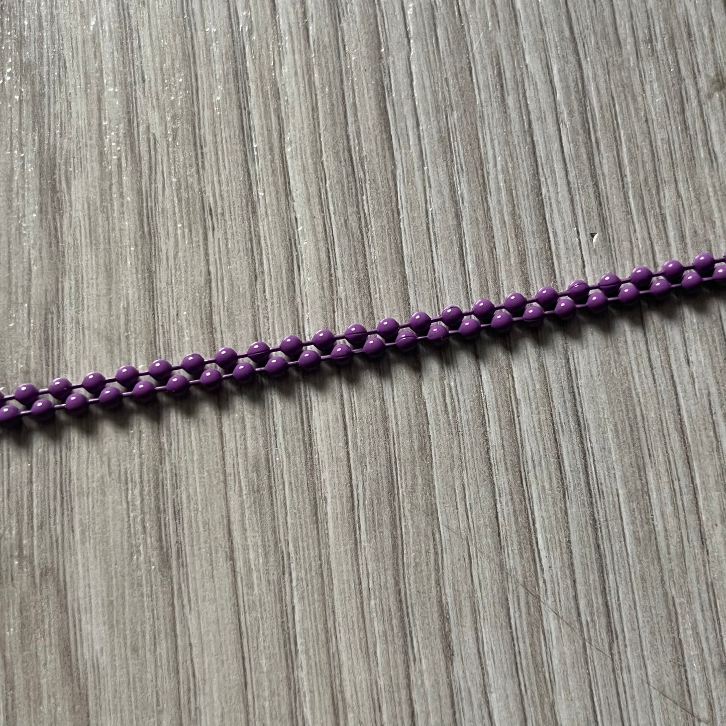 The Chrome Hearts 'Silichrome' Cross Purple Necklace showcases a silicone cross pendant with embossed CH lettering, twin cross graphics on the back, and a 2019 anniversary mark. Offered only through CH flagship stores, it comes paired with a purple ball chain and includes both the dustbag and paper receipt.