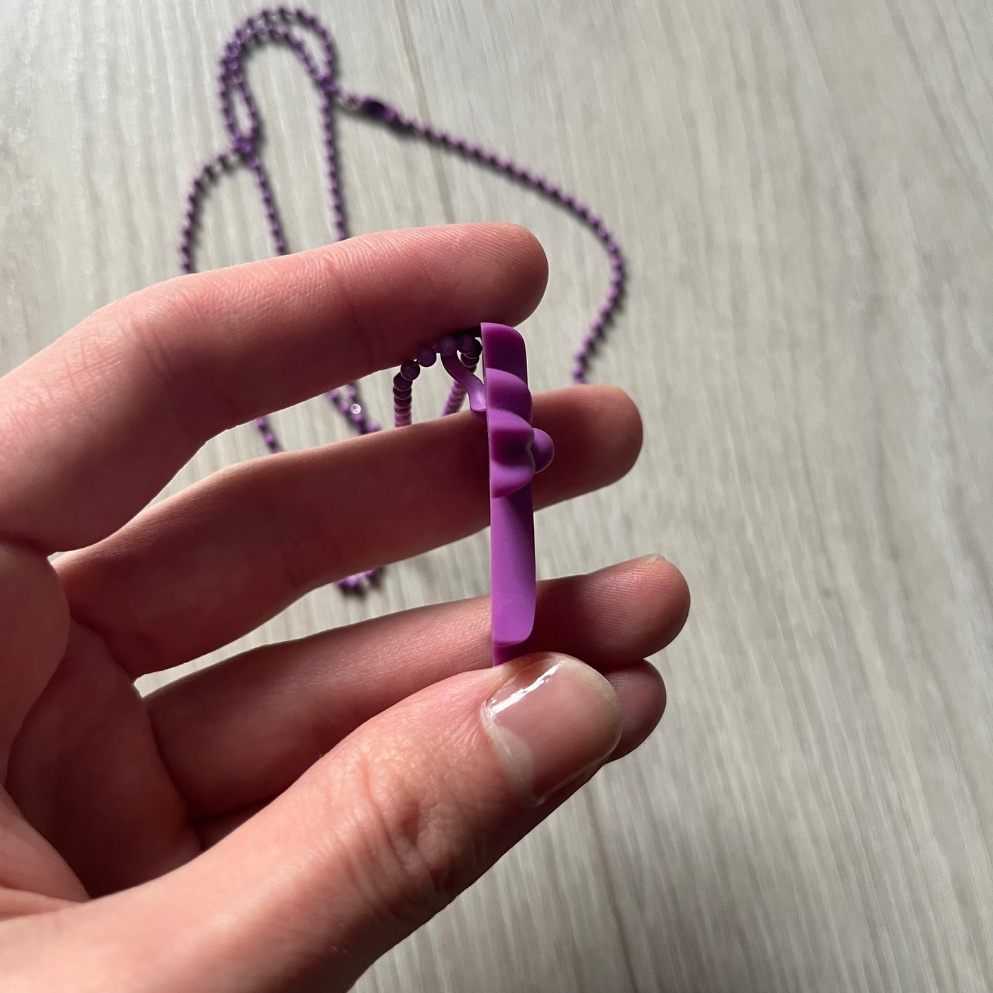 The Chrome Hearts 'Silichrome' Cross Purple Necklace showcases a silicone cross pendant with embossed CH lettering, twin cross graphics on the back, and a 2019 anniversary mark. Offered only through CH flagship stores, it comes paired with a purple ball chain and includes both the dustbag and paper receipt.