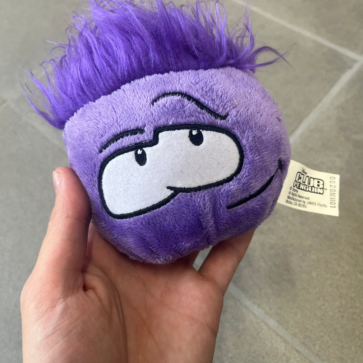 Club Penguin Series 2 Purple Puffle Plushie was Released in 2009 by Disney and Jakks Pacific, featuring a smirking looking up embroidered face, troll-like hair and a half plush half beanie body. It comes with a Disney-licensed tag.