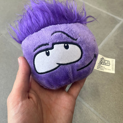 Club Penguin Series 2 Purple Puffle Plushie was Released in 2009 by Disney and Jakks Pacific, featuring a smirking looking up embroidered face, troll-like hair and a half plush half beanie body. It comes with a Disney-licensed tag.