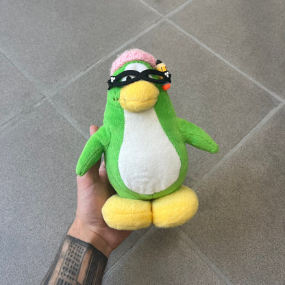 Club Penguin 2009 Series 3 Aunt Arctic Penguin Plushie is a green penguin with a pink beanie, freckles, black eyeglasses and a pencil next to the ear. Released in [year] by Disney and Jakks Pacific, featuring an embroidered Club Penguin logo on the bottom of the foot. It comes with a Disney-licensed tag.