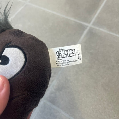Club Penguin Series 4 Black Puffle Plushie was Released in 2009 by Disney and Jakks Pacific, featuring an angry embroidered face, troll-like hair and a half plush half beanie body. It comes with a Disney-licensed tag.