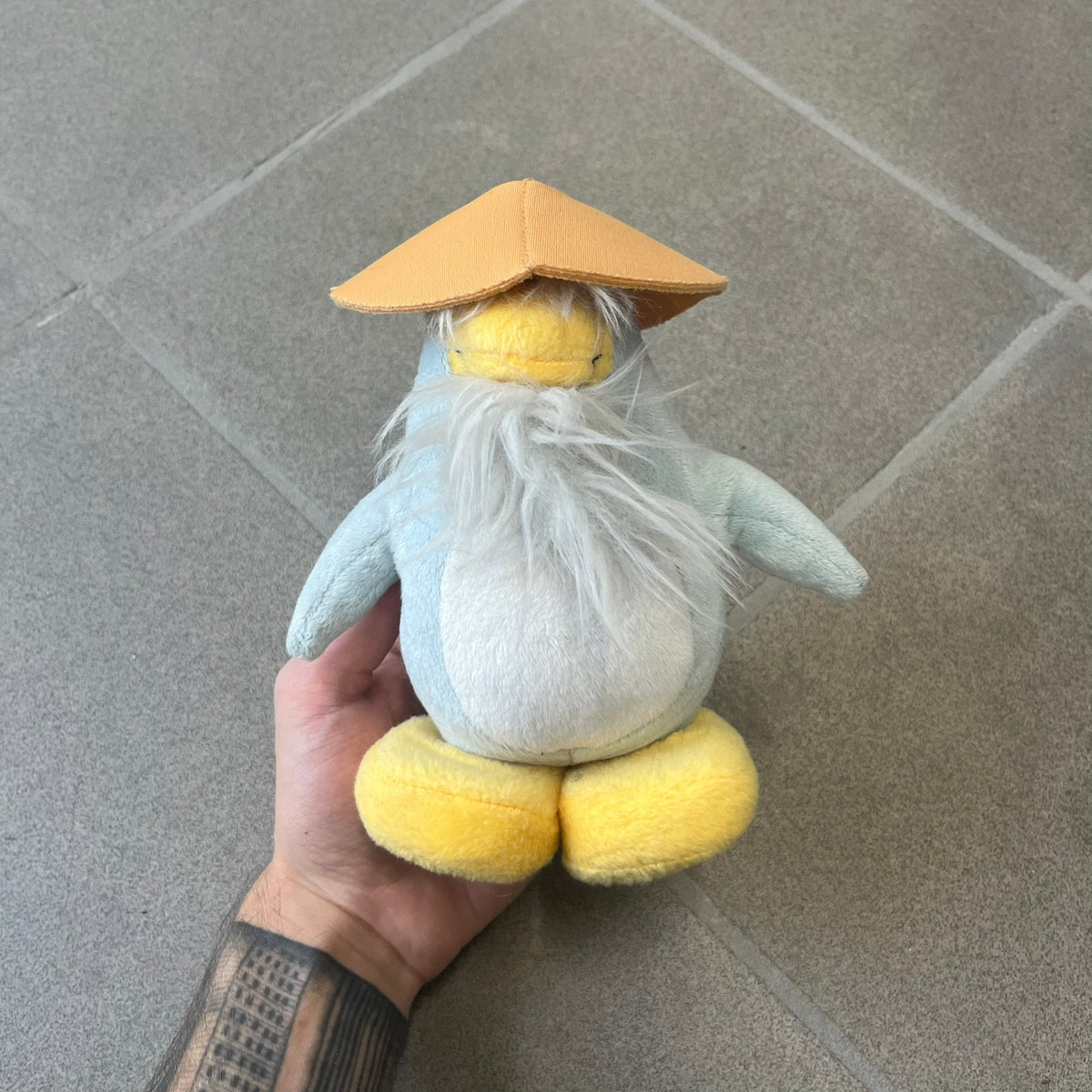 Club Penguin 2009 Series 4 Sensei Penguin Plushie is a gray penguin with a straw hat and long gray beard. Released in 2009 by Disney and Jakks Pacific, featuring an embroidered Club Penguin logo on the bottom of the foot. It comes with a Disney-licensed tag.
