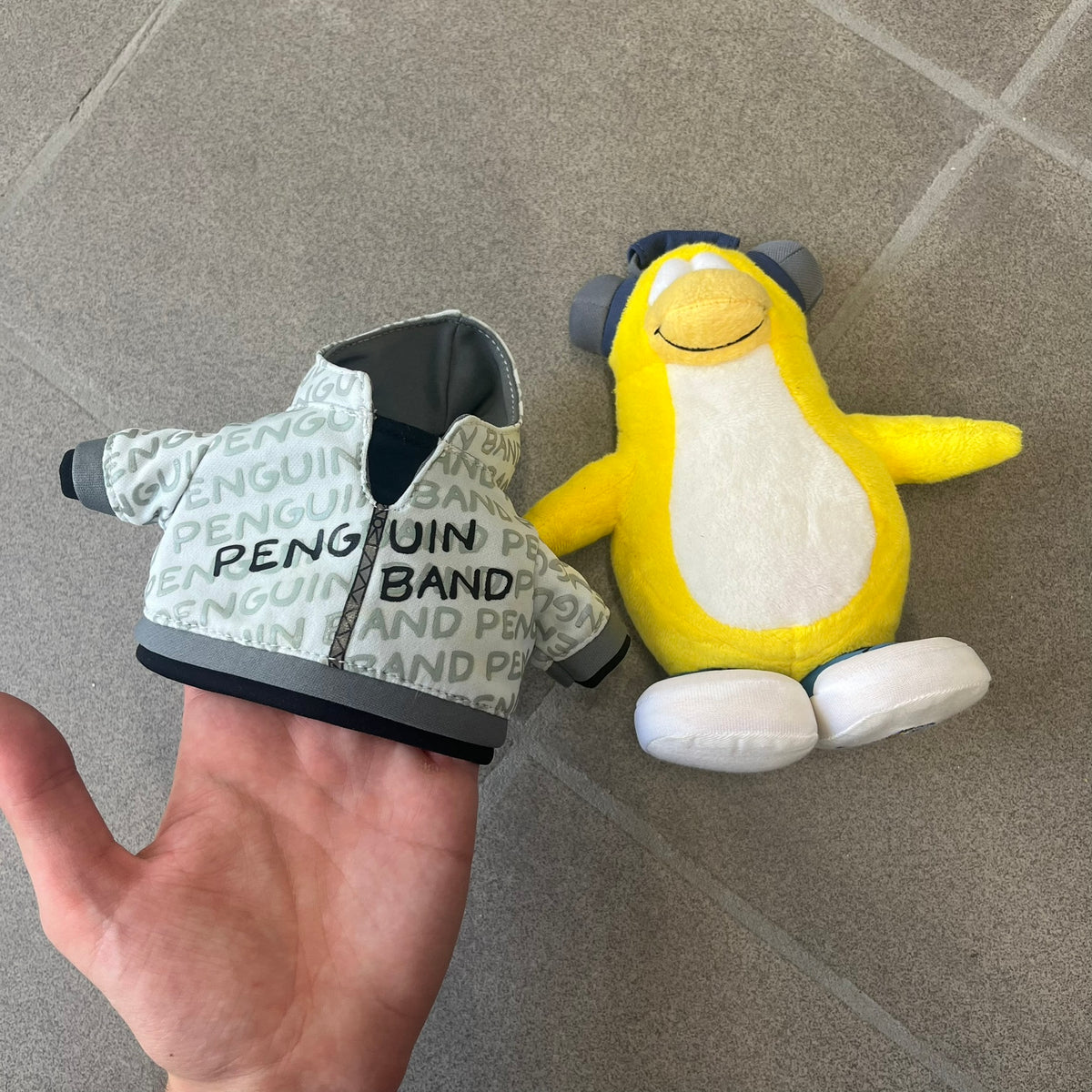Club Penguin 2010 Series 7 Band Member Penguin Plushie is a yellow penguin with 3D Headphones and a jacket that can be taken off. Released in 2010 by Disney and Jakks Pacific, featuring an embroidered Club Penguin logo on the bottom of the foot. It comes with a Disney-licensed tag.