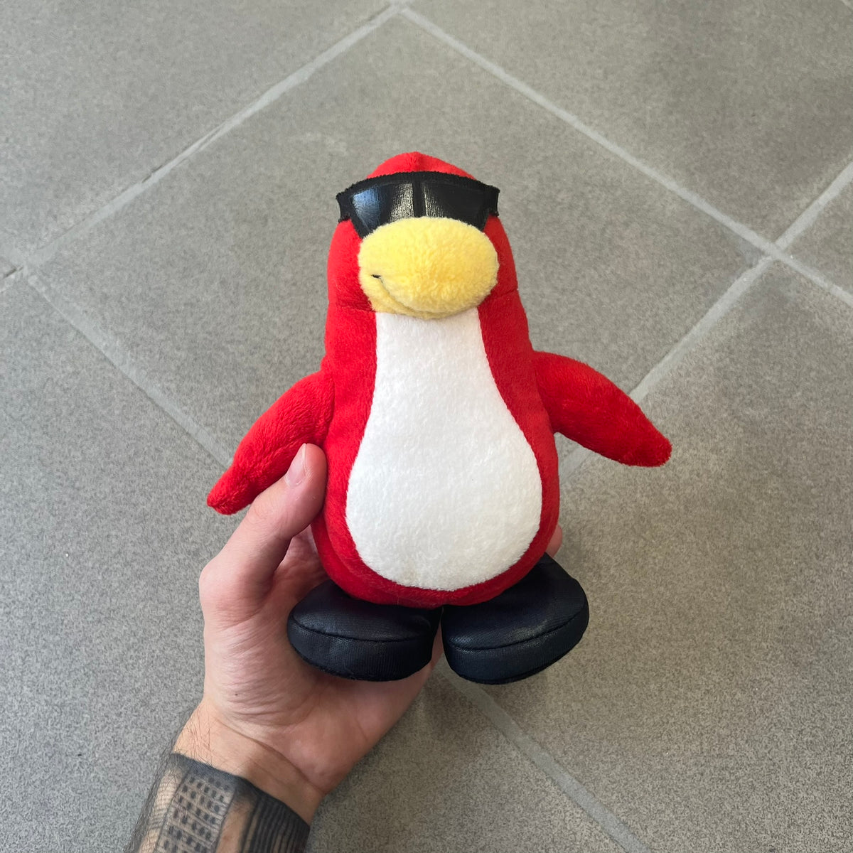 Club Penguin 2010 Series 7 Secret Agent Penguin Plushie is a red penguin with black sunglasses on. He originally had a tuxedo. Released in 2010 by Disney and Jakks Pacific, featuring an embroidered Club Penguin logo on the bottom of the foot. It comes with a Disney-licensed tag.