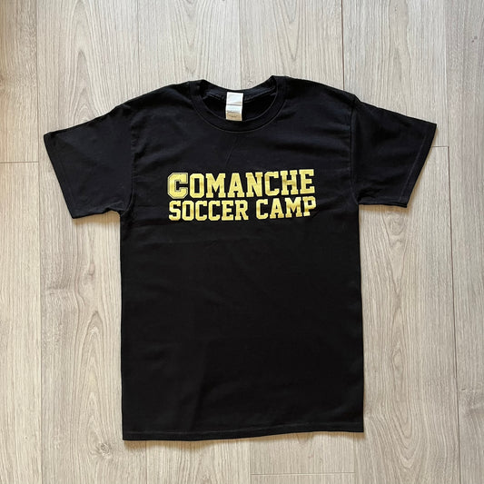 Black t-shirt with 'Comanche Soccer Camp' text on a wooden floor