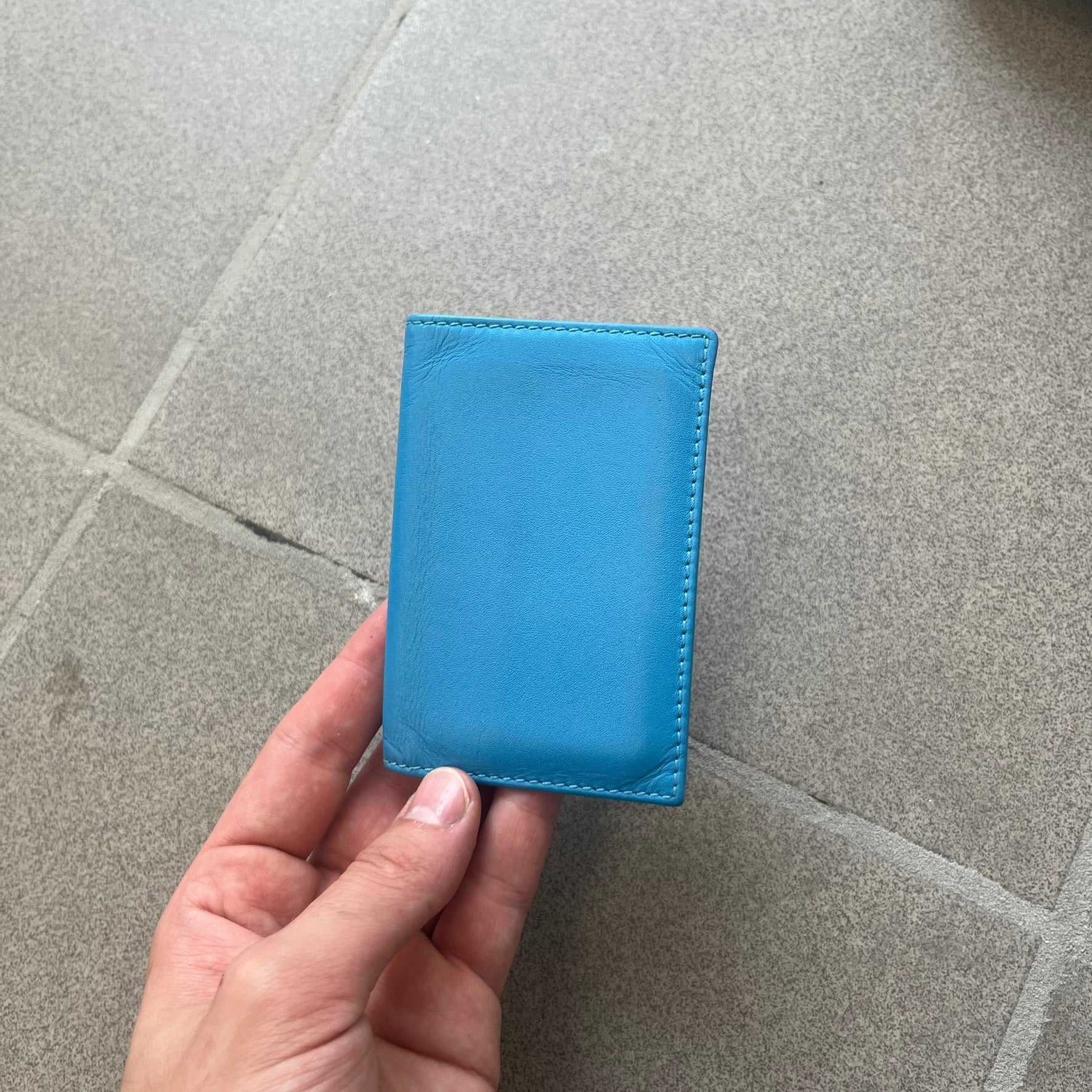 Comme des Garçons Blue Bifold Leather Wallet features a clean and minimal bi-fold design crafted from smooth aqua blue calf leather. The interior includes multiple card slots, a banknote compartment, and a gold-tone Comme des Garçons logo stamp for a subtle branded detail. A timeless everyday accessory combining practical organization with the brand’s signature minimalist aesthetic.
