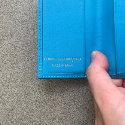 Comme des Garçons Blue Bifold Leather Wallet features a clean and minimal bi-fold design crafted from smooth aqua blue calf leather. The interior includes multiple card slots, a banknote compartment, and a gold-tone Comme des Garçons logo stamp for a subtle branded detail. A timeless everyday accessory combining practical organization with the brand’s signature minimalist aesthetic.
