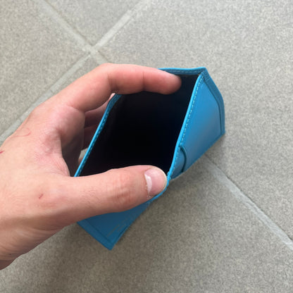 Comme des Garçons Blue Bifold Leather Wallet features a clean and minimal bi-fold design crafted from smooth aqua blue calf leather. The interior includes multiple card slots, a banknote compartment, and a gold-tone Comme des Garçons logo stamp for a subtle branded detail. A timeless everyday accessory combining practical organization with the brand’s signature minimalist aesthetic.
