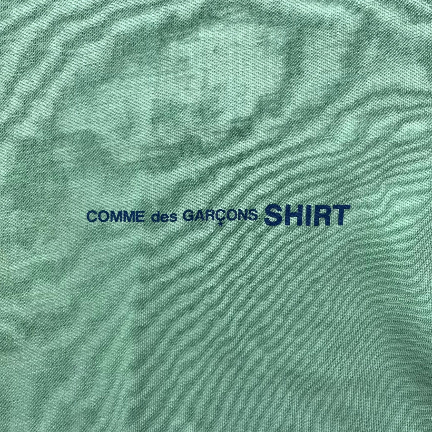 Green shirt with 'COMME des GARÇONS SHIRT' text in blue.