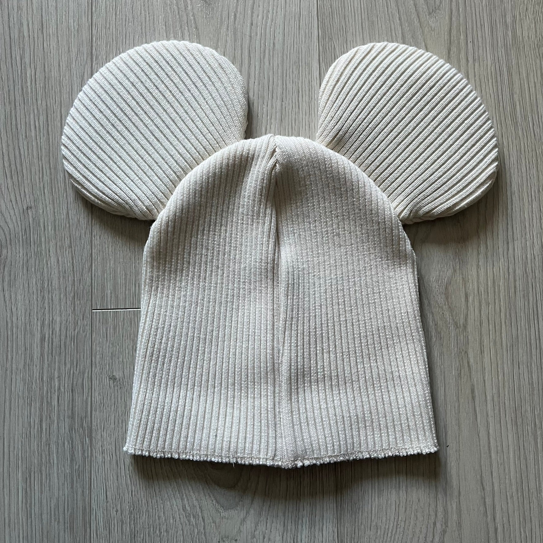 Released in Autumn/Winter 2018, this Comme des Garçons beanie playfully reimagines the classic knit hat with ‘Mickey Mouse’-inspired ears. Crafted in an off-white shade with ribbed detailing, it balances fun design with signature CDG avant-garde flair. A standout seasonal accessory with a collectible edge.