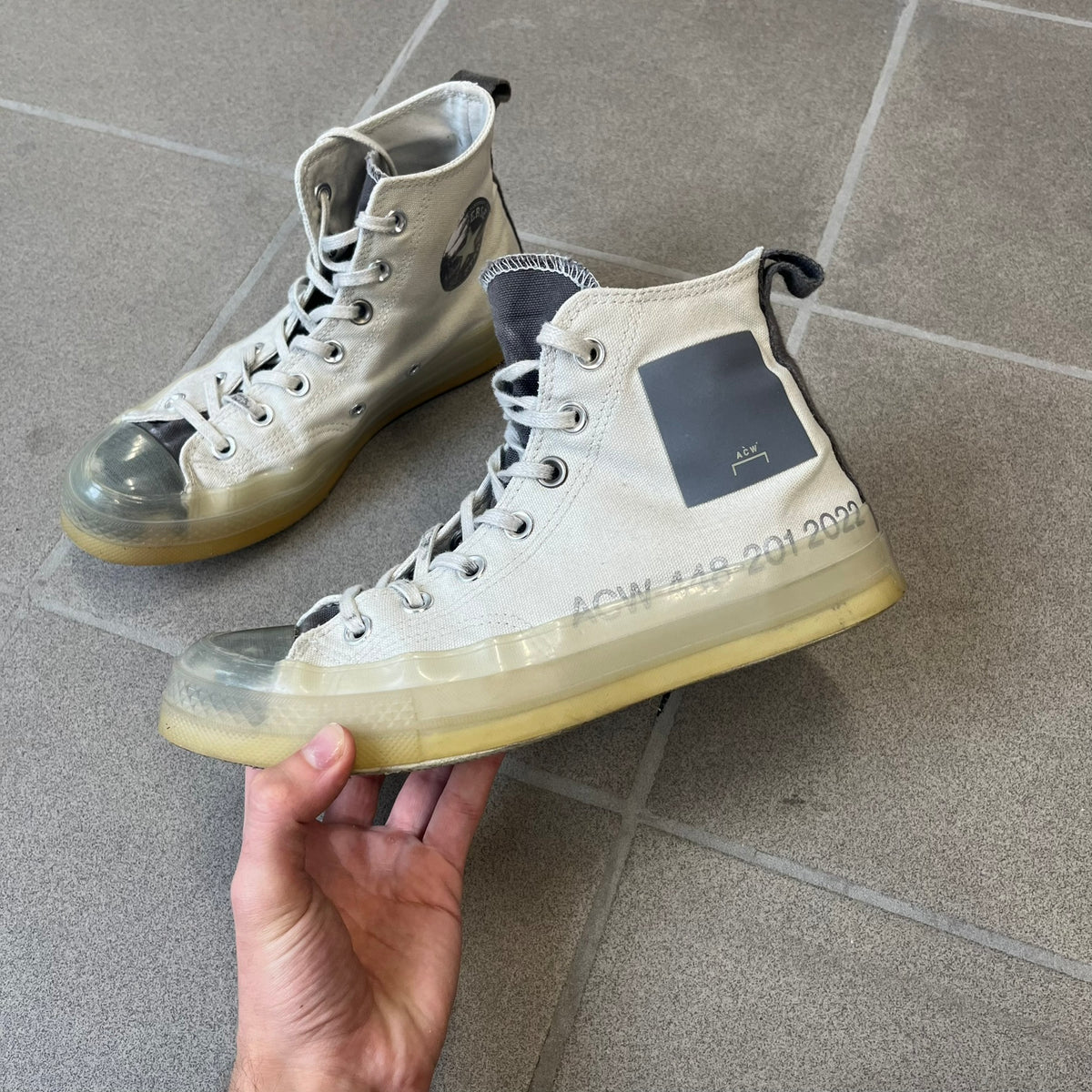 Converse x A-COLD-WALL* Silver Birch Chuck 70 (A02276C) is a limited-edition high-top sneaker from the collaboration with British designer Samuel Ross, released October 6, 2022 in a Silver Birch/Pavement colorway. The canvas upper features a rubber toe cap and a Converse heel plate, with a distinctive translucent, marbled speckled sole.
