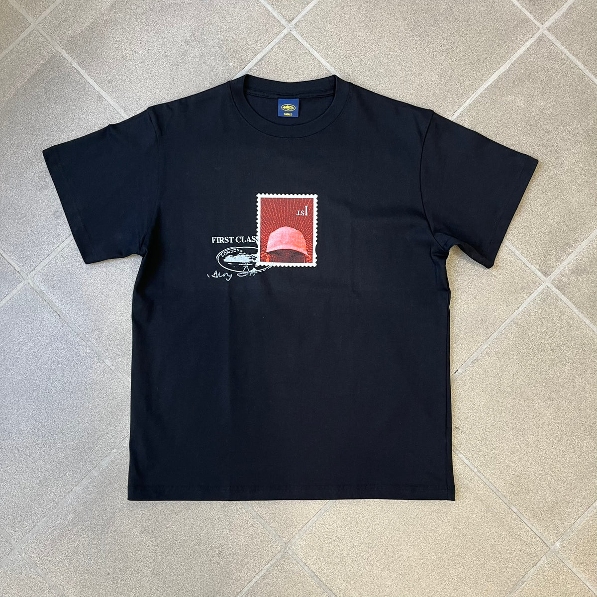 Corteiz x Skepta Konnichiwa 10th Anniversary BlackTee is a 100% cotton T-shirt released to mark the 10th anniversary of Skepta's "Konnichiwa" album, featuring the original album cover artwork with a red postage stamp graphic of Skepta. The design includes a "First Class" ink stamp alongside the Corteiz logo replacing the original cover's "London" mark.