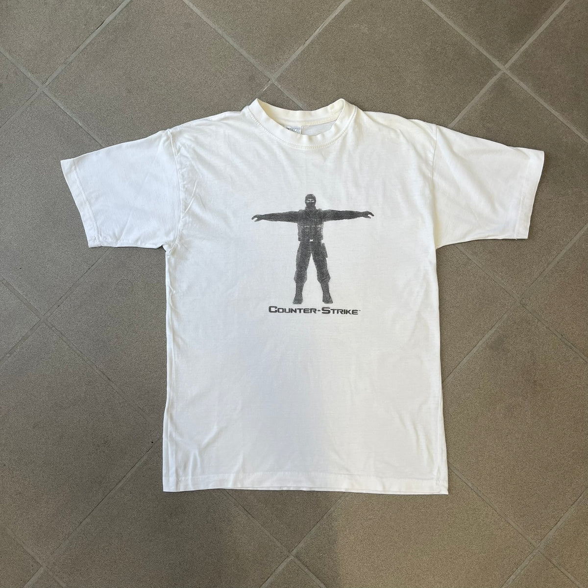 Counter Strike 1.6 Bootleg White Tee is a white, 100% cotton European bootleg made on an "American" blank, featuring a CS 1.6 counter-terrorist model standing with his arms out on the front with "Counter-Strike" text printed below.