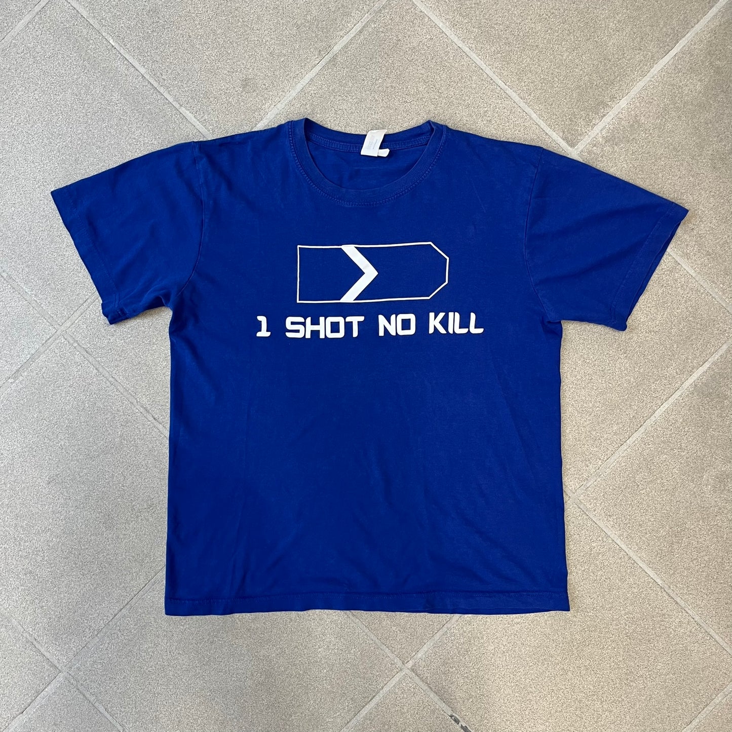 Counter Strike “1 Shot No Kill” Blue Tee features a blue T-shirt made on a Piccolio blank. The front has a Counter-Strike Silver 1 rank graphic with a white “1 Shot No Kill” text underneath. This is not an official Valve release.