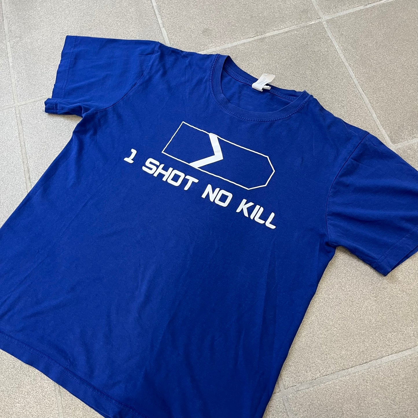 Counter Strike “1 Shot No Kill” Blue Tee features a blue T-shirt made on a Piccolio blank. The front has a Counter-Strike Silver 1 rank graphic with a white “1 Shot No Kill” text underneath. This is not an official Valve release.