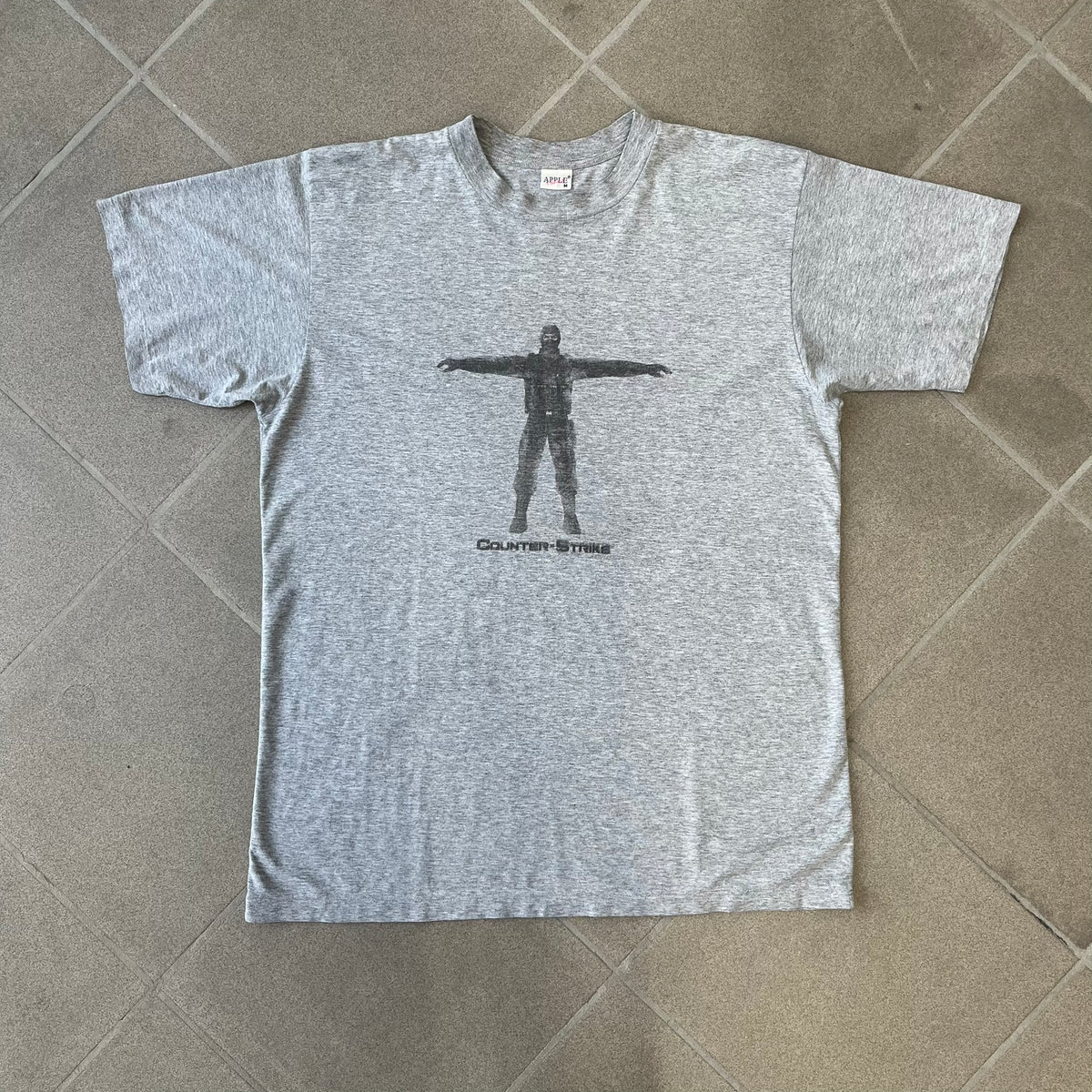 Counter Strike 2000's Bootleg Gray Tee is a gray, 100% cotton European bootleg made in Greece on an "Apple T-Shirt" blank, featuring a CS 1.6 counter-terrorist model T-posing on the front with "Counter-Strike" text printed below.