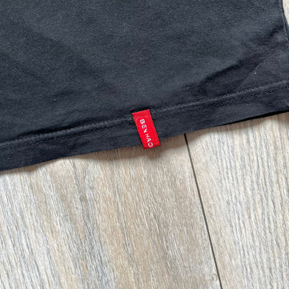 Counter-Strike 2000s Logo Tee is a black T-shirt featuring the classic Counter-Strike logo printed across the front. The design includes white “Counter” and “Strike” text separated by the armed character silhouette, with a red shadow layer behind the logo. A small red Ben Hao tag is attached near the bottom hem.
