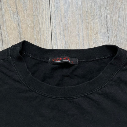 Counter-Strike 2000s Logo Tee is a black T-shirt featuring the classic Counter-Strike logo printed across the front. The design includes white “Counter” and “Strike” text separated by the armed character silhouette, with a red shadow layer behind the logo. A small red Ben Hao tag is attached near the bottom hem.