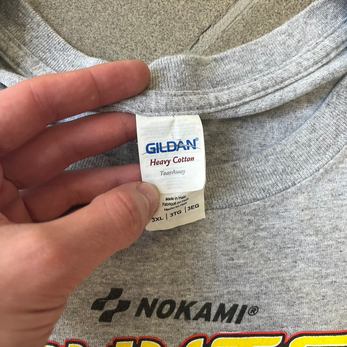 Counter Strike 2015 Arcade Block Gray Tee is a gray T-shirt featuring two Counter-Terrorists in yellow tones on a red background, with a yellow Counter-Strike text logo and a Nokami logo above the graphic. Two “Notindendo” logos sit on either side of the artwork. The shirt was available in the 2015 Arcade Block, specifically in the Nerd Block.