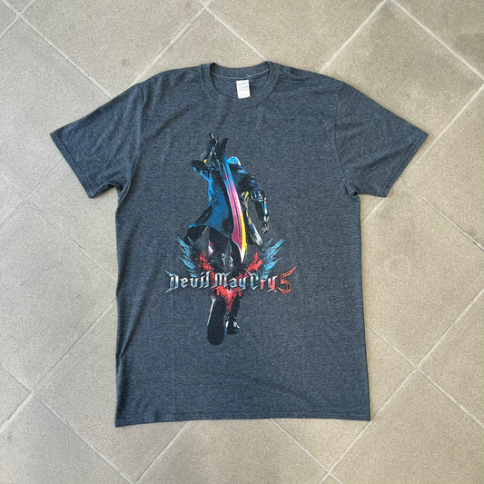 Devil May Cry 5 Promo 2019 Gray Tee is made on a Gildan blank in grey cotton. The front features the Devil May Cry 5 game cover but only with Nero holding his sword, along with large “Devil May Cry 5” text. Made as a promotional T-shirt for the game.