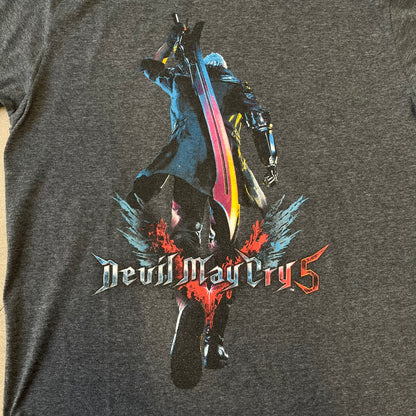 Devil May Cry 5 Promo 2019 Gray Tee is made on a Gildan blank in grey cotton. The front features the Devil May Cry 5 game cover but only with Nero holding his sword, along with large “Devil May Cry 5” text. Made as a promotional T-shirt for the game.