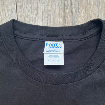 Dexter “Blood Never Lies” 2017 Tee is a black T-shirt featuring a front graphic with red blood-style “Dexter” and “Blood Never Lies” text. Between the texts, the print shows blood-covered tools with Dexter visible in the reflection of a saw. Small 2017 Showtime licensing text appears beneath the graphic, confirming official series merchandise.