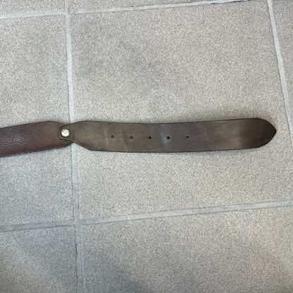 Diesel 2000's Brown Leather Belt features a brown 100% cow leather construction with a simple silver-tone buckle. A small leather piece with Diesel text is attached to the buckle and rotates freely. The belt is marked “Extra Tough,” with gold Diesel text printed on the inside. Made in Italy, with an additional attached section at the end for adjusting the length.
